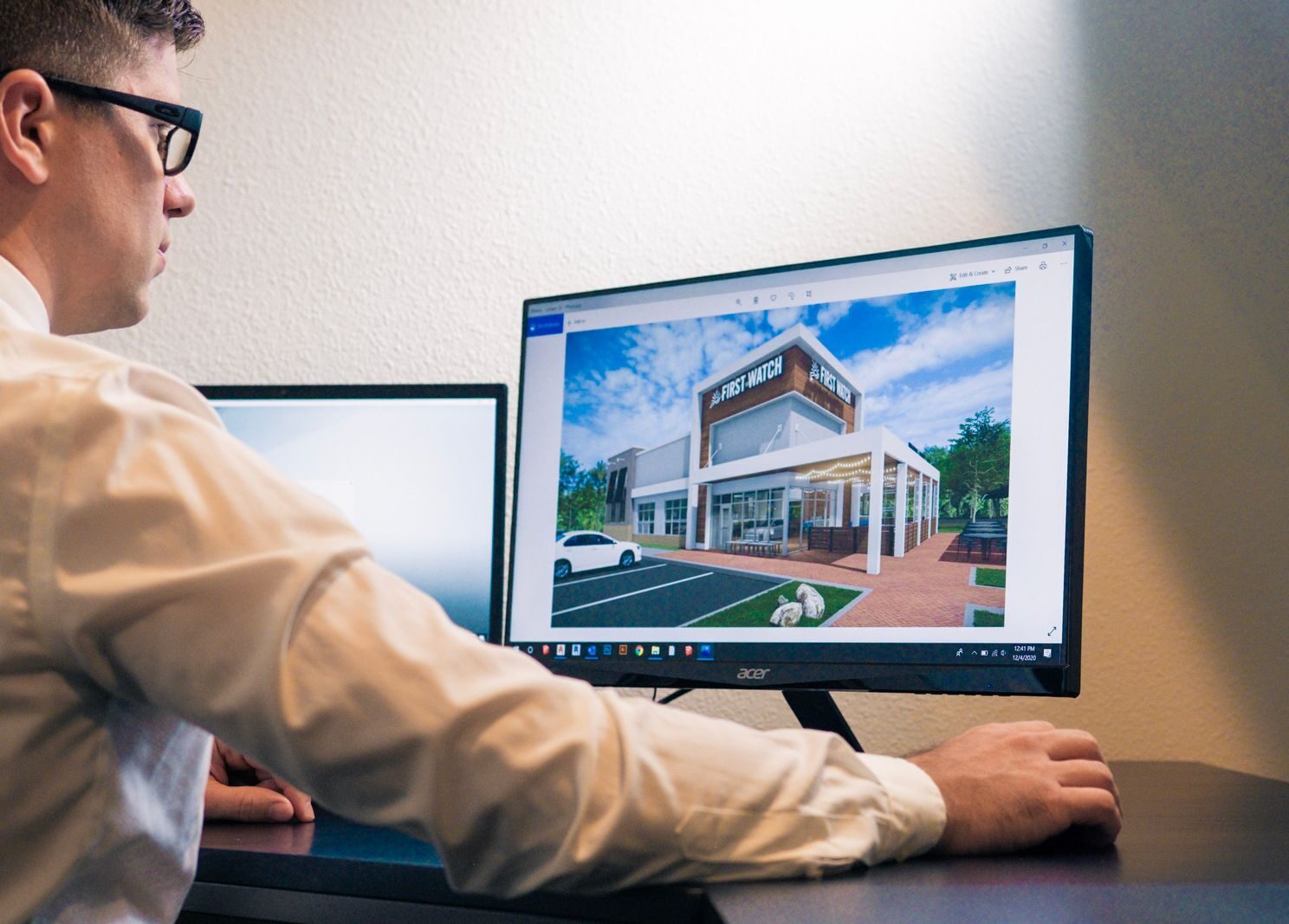 Architect evaluating a building design on a computer screen in an office setting.